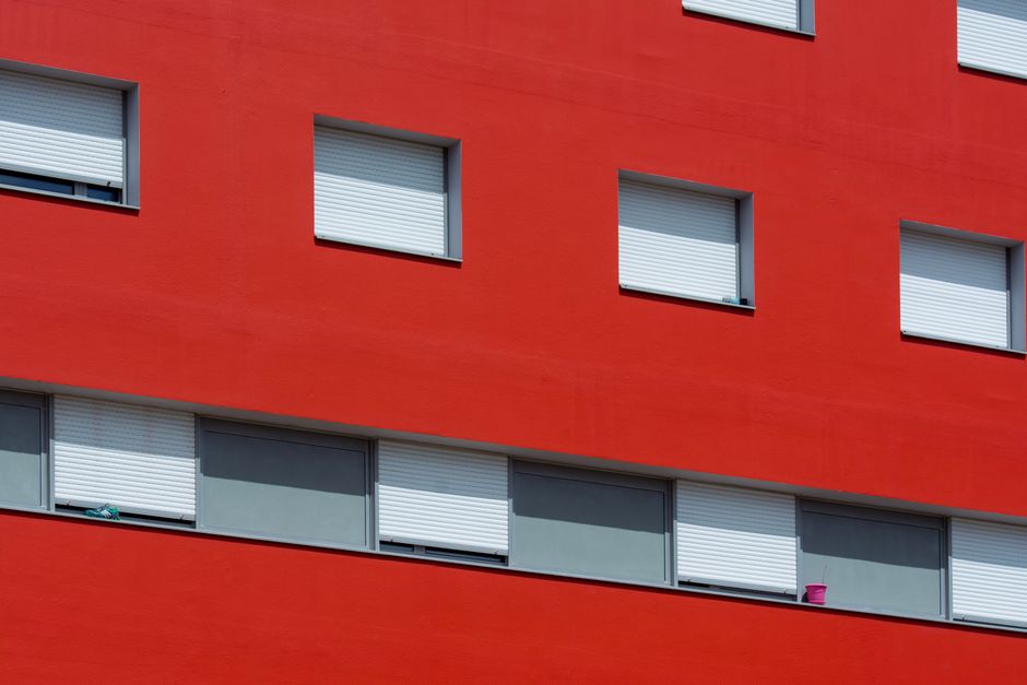 Painted house exterior with closed shutters in bright sun