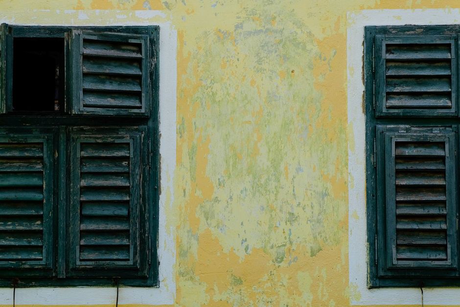 Weathered wooden louvered shutters on a painted wall